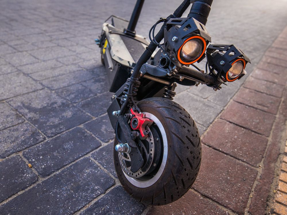 A large e-scooter with twin headlights, a suspension fork and a wide tyre