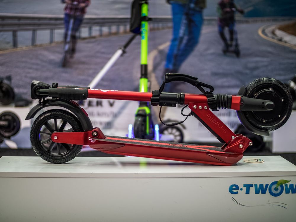 A red e-scooter folded flat on a display stand