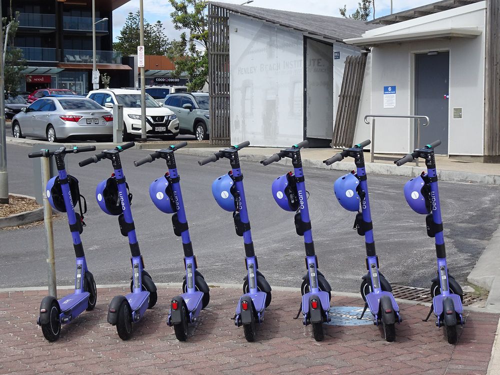 A row of purple hire e-scooters with helmets attached, parked on a footpath a South Australia